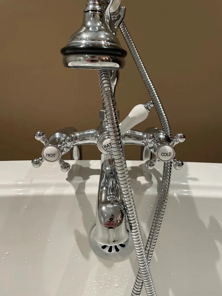Chrome tub faucet with hand shower over a white tub