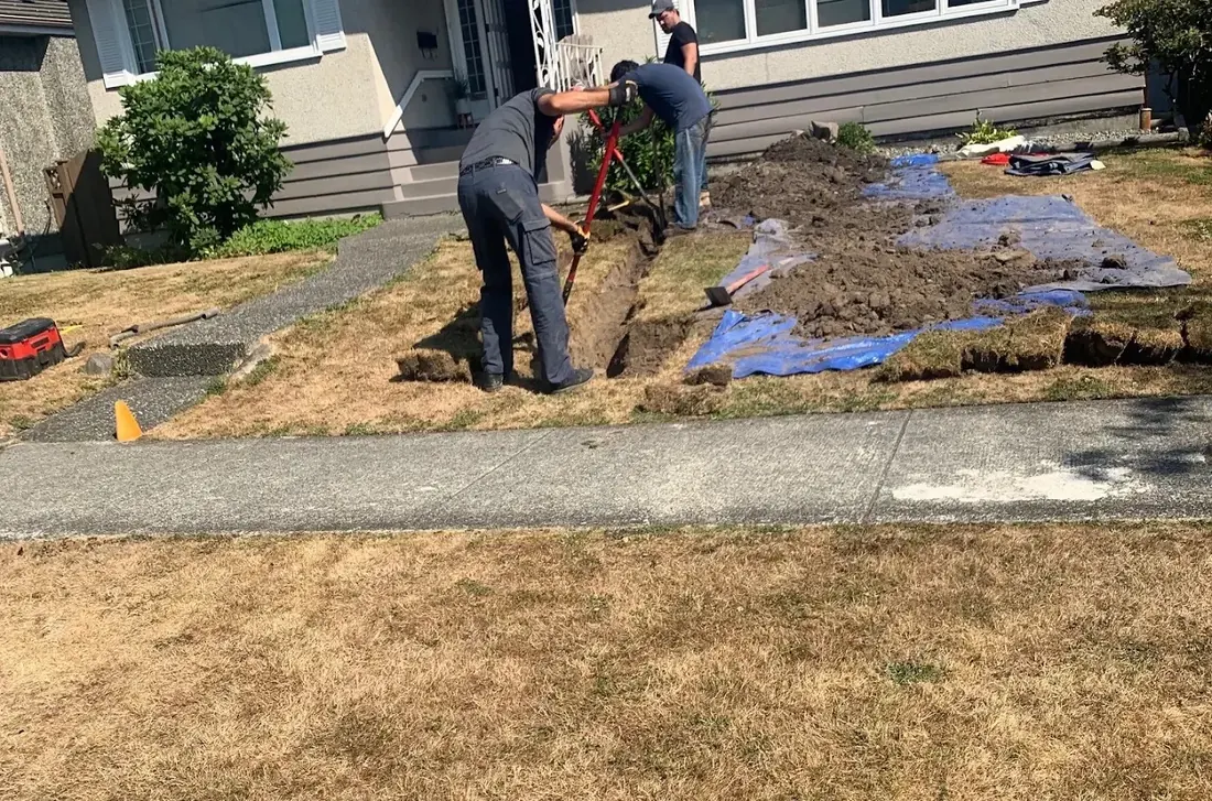 Crew digging a trench across a front lawn for underground line work