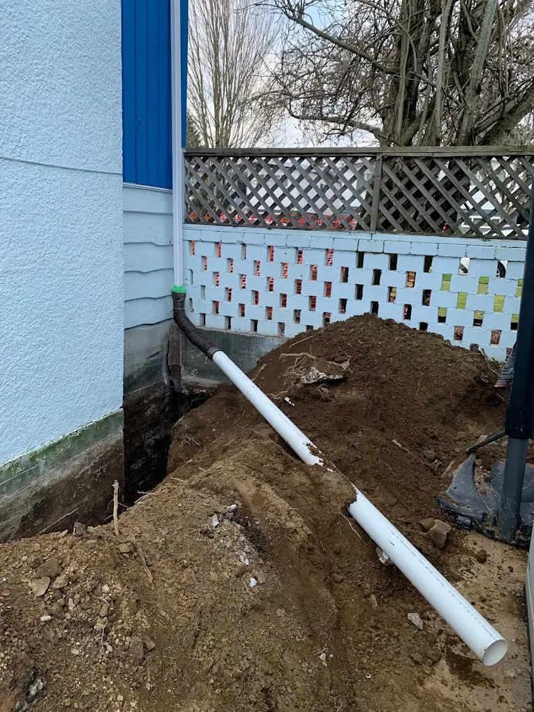 White PVC drain line from a downspout laid in a trench