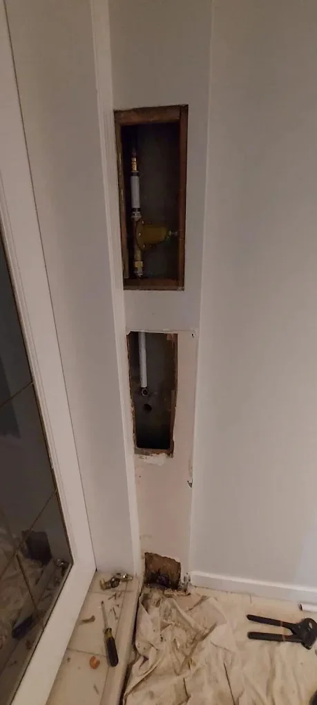 Wall opened up to reach a pipe and brass valve for repair