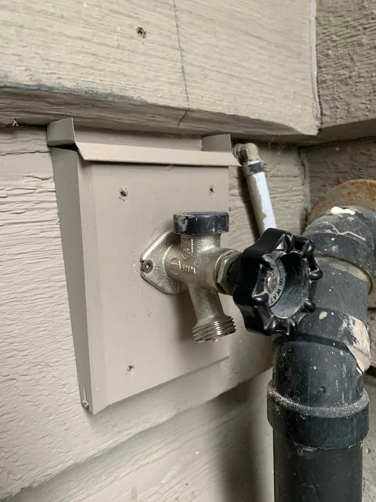 Outdoor hose bib on the side of a house