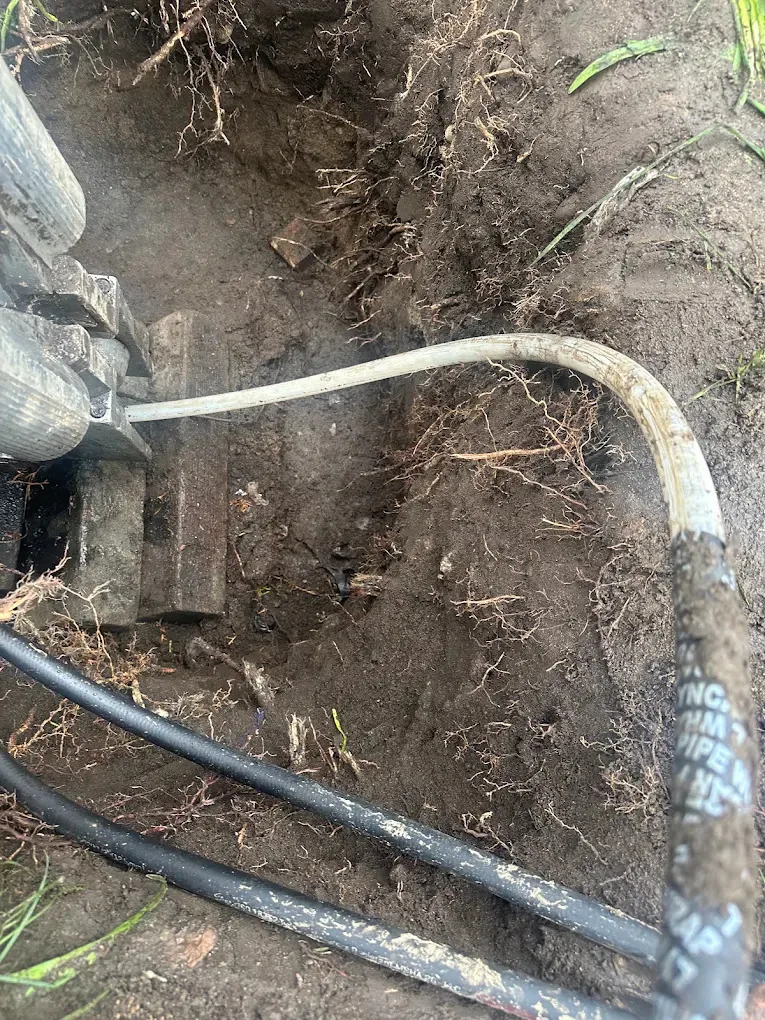 Excavated hole with a water line and tools in the ground